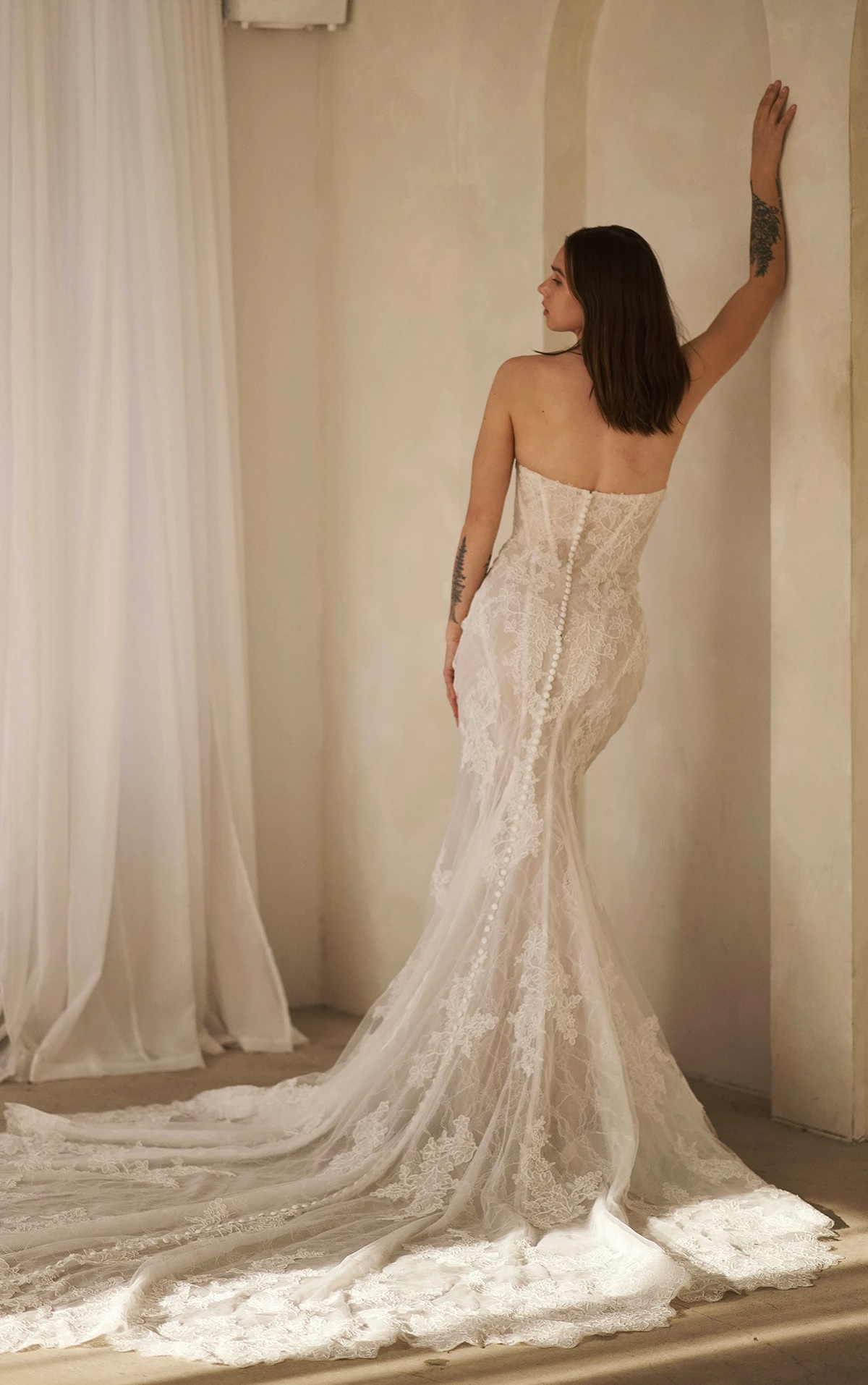 A bride shows the back of her 1752 wedding dress by Martina Liana. It is a lace bridal gown with a sweetheart neckline