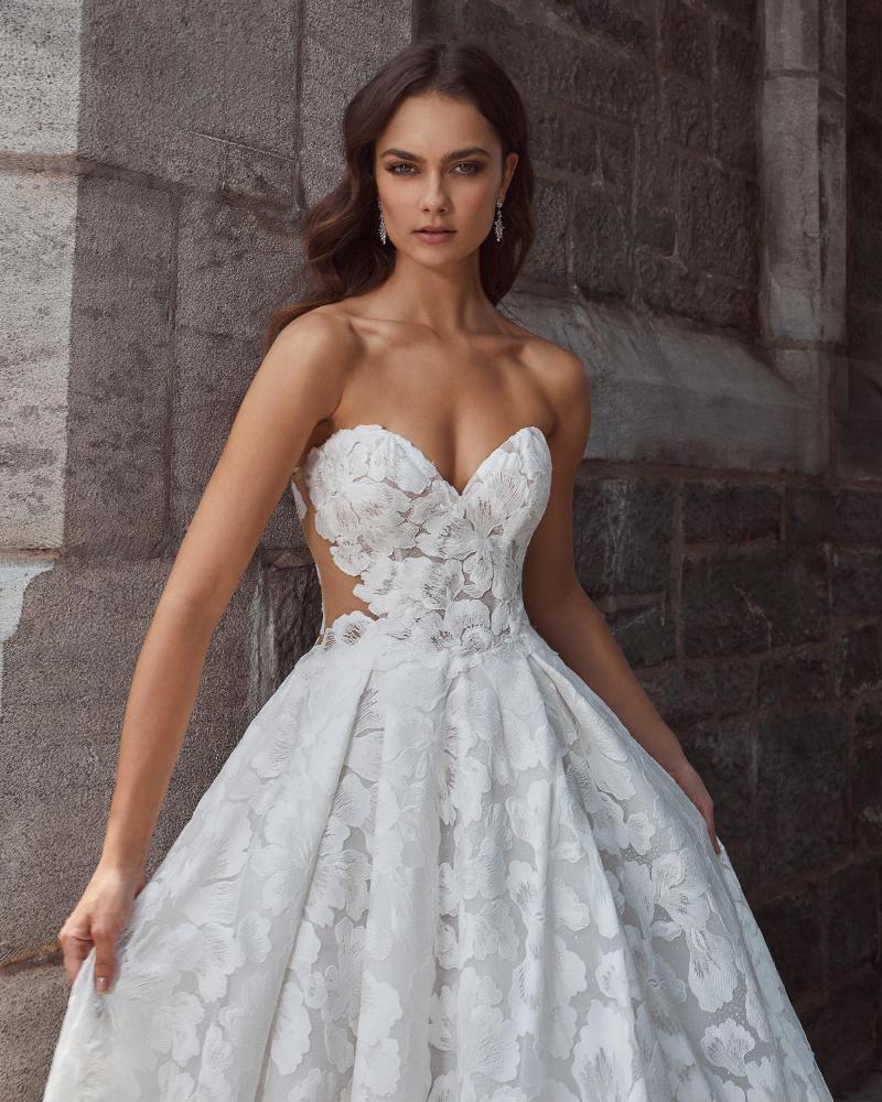 Mid-ground view of a model wearing a romantic sweetheart ballgown wedding dress with delicate floral lace and a soft train from bridal shop Mira Couture in Chicago