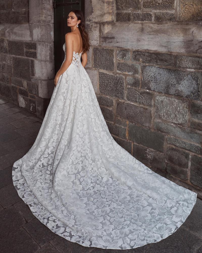 A model shows the open back and train of her whimsical A-line gown