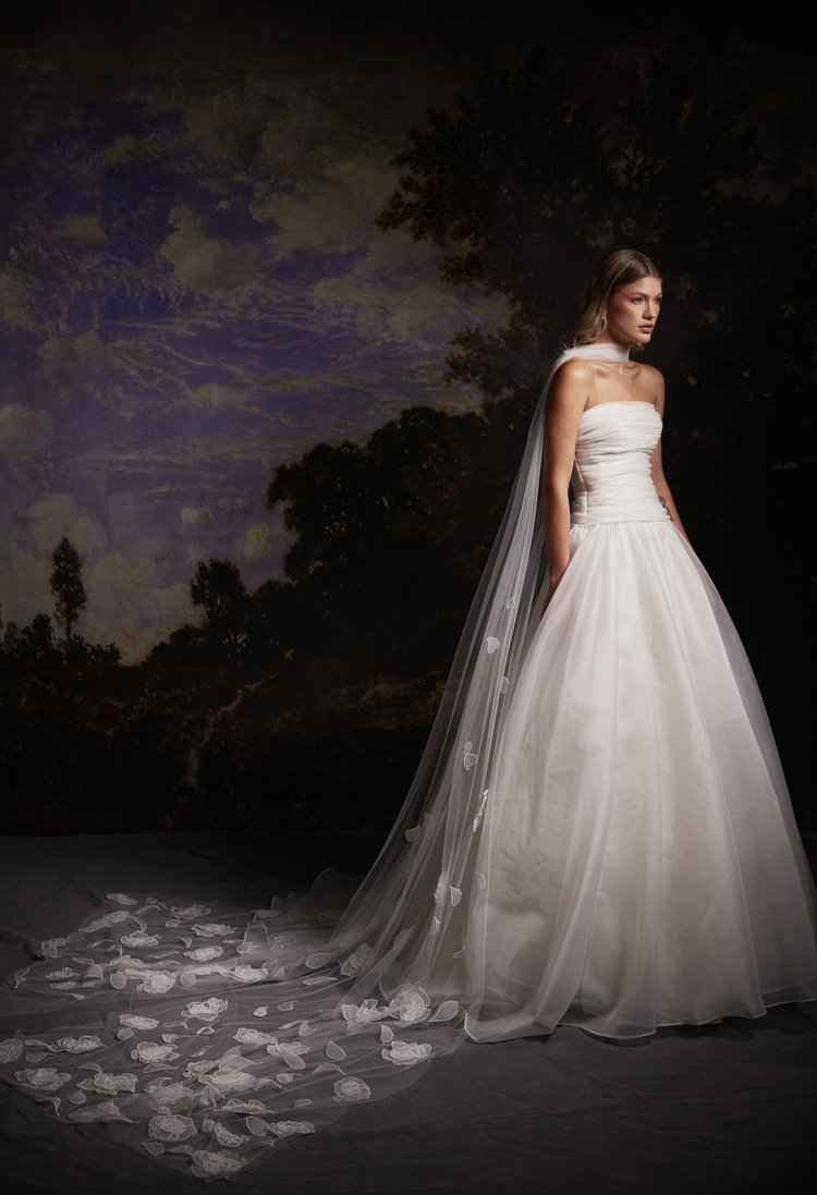 A woman in a wedding dress stands gracefully in front of a large